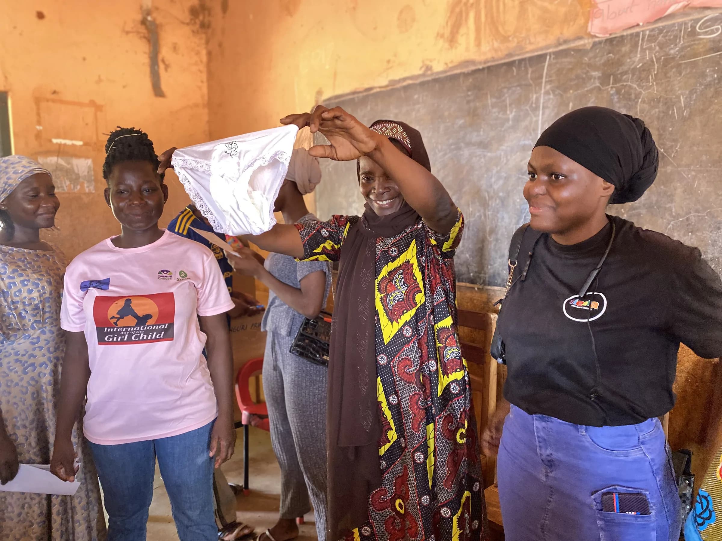 Women and girls look at reusable menstrual products together during a classroom session