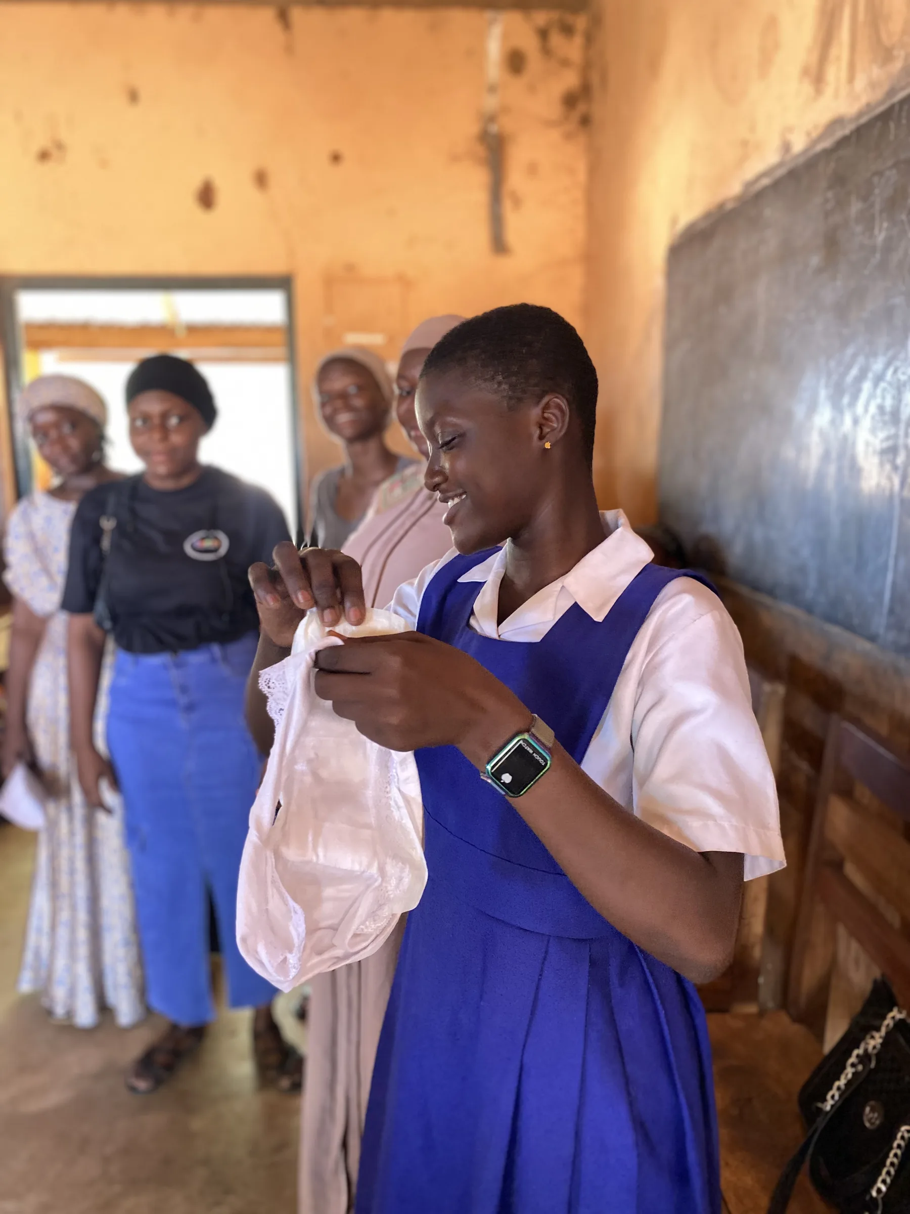 A schoolgirl examines a reusable sanitary pad during a menstrual health session in her classroom