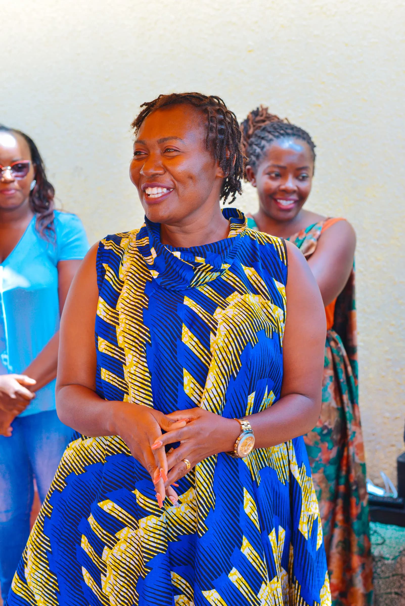 Women in vibrant African prints smile together at a gathering